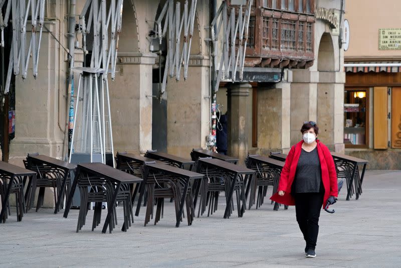 A masked woman walks past a closed bar after the Navarran local government limited all non-essential movement in and out of the region