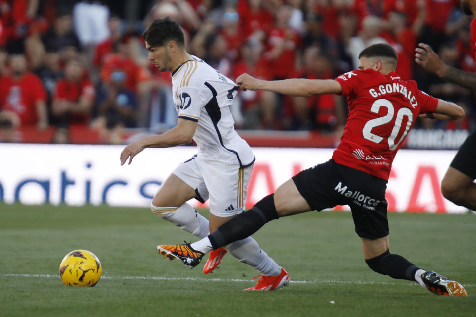 Real Madrid's Brahim Diaz, right, gets his shirt pulled by Mallorca's Giovanni Gonzalez, centre, during a Spanish La Liga soccer match between Mallorca and Real Madrid at the Son Moix stadium in Palma de Mallorca, Spain, Saturday, April 13, 2024. (AP Photo/Francisco Ubilla)