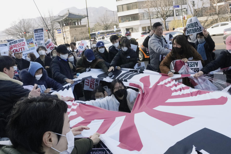 Protesters tear a banner with the Japanese rising-sun flag during a rally against the South Korean government's move to improve relations with Japan, in front of the Japanese Embassy in Seoul, South Korea, Wednesday, March 1, 2023. South Korea's president on Wednesday called Japan "a partner that shares the same universal values" and renewed hopes to repair ties frayed over Japan's colonial rule of the Korean Peninsula. (AP Photo/Ahn Young-joon)