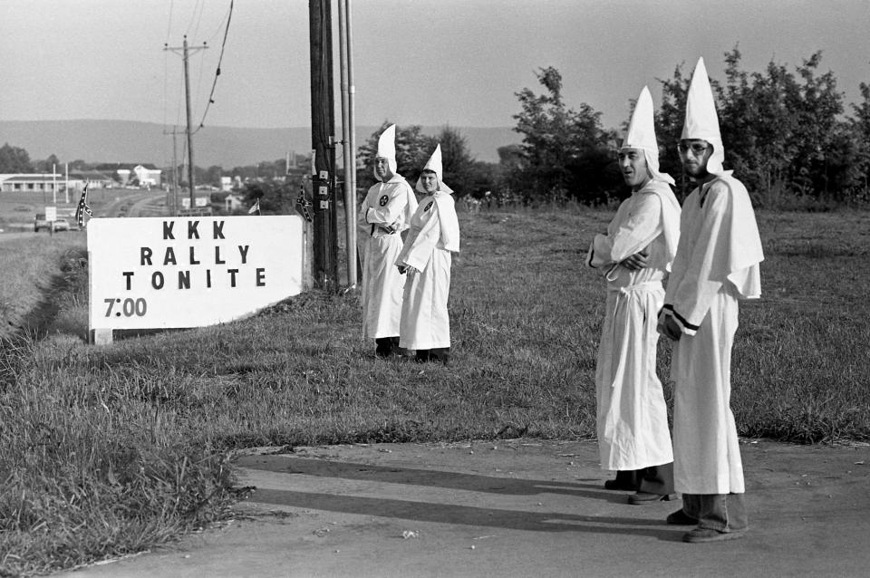 Some Ku Klux Klan members keep an eye out for folks gathering in Decherd, Tenn. July 14, 1979 for a KKK rally. More than 300 showed up for the rally and cross burning.
