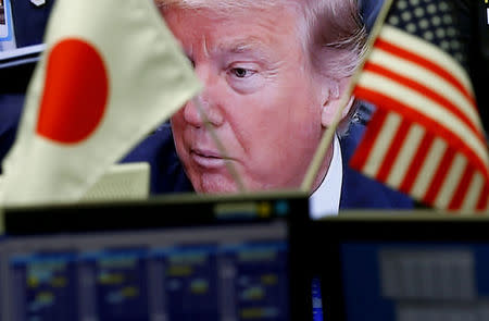 FILE PHOTO: A TV monitor showing U.S. President Donald Trump is seen through national flags of the U.S. and Japan at a foreign exchange trading company in Tokyo, Japan February 1, 2017. REUTERS/Kim Kyung-Hoon/File Photo