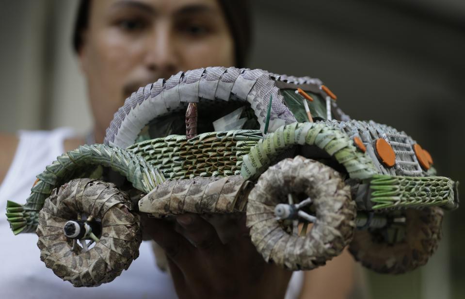 FILE - Venezuelan migrant Edixon Infante shows a handicraft made with devalued Venezuelan currency, in Cucuta, Colombia, Feb. 6, 2019. (AP Photo/Fernando Vergara, File)