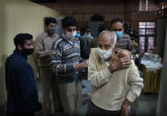 An elderly man leaves after getting Covid-19 vaccination at a makeshift center in a government school in New Delhi, India, Friday, Jan. 28, 2022. Indian health officials said that the first signs of COVID-19 infections plateauing in some parts of the vast country were being seen, but cautioned that cases were still surging in some states. (AP Photo/Manish Swarup)