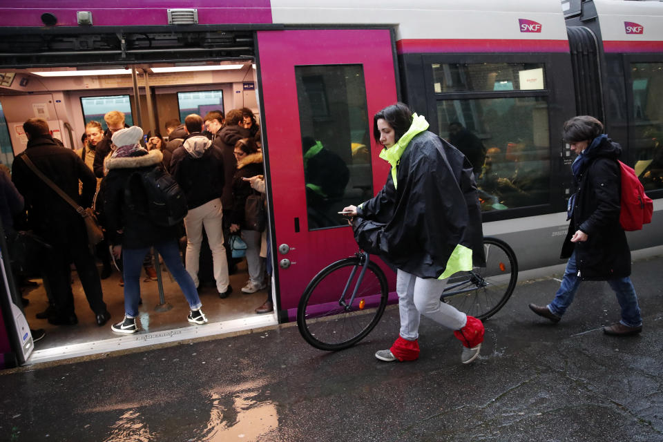 Commuters walk to get on a train at the Gare Saint Lazare station in Paris, France, Monday, Dec. 16, 2019. French transport strikes against a planned overhaul of the pension system entered their twelfth day Monday as French president Emmanuel Macron's government remains determined to push ahead with its plans. (AP Photo/Francois Mori)