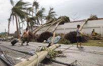 Survivors walks past uprooted palm trees after super Typhoon Haiyan battered Tacloban city, central Philippines November 9, 2013. Typhoon Haiyan, the strongest typhoon in the world this year and possibly the most powerful ever to hit land battered the central Philippines on Friday, forcing millions of people to flee to safer ground, cutting power lines and blowing apart houses. Haiyan, a category-5 super typhoon, bore down on the northern tip of Cebu Province, a popular tourist destination with the country's second-largest city, after lashing the islands of Leyte and Samar with 275 kph (170 mph) wind gusts and 5-6 meter (15-19 ft) waves. REUTERS/Romeo Ranoco (PHILIPPINES - Tags: DISASTER ENVIRONMENT TPX IMAGES OF THE DAY)