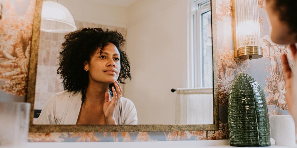 a beautiful woman examines her skin in a bathroom mirror