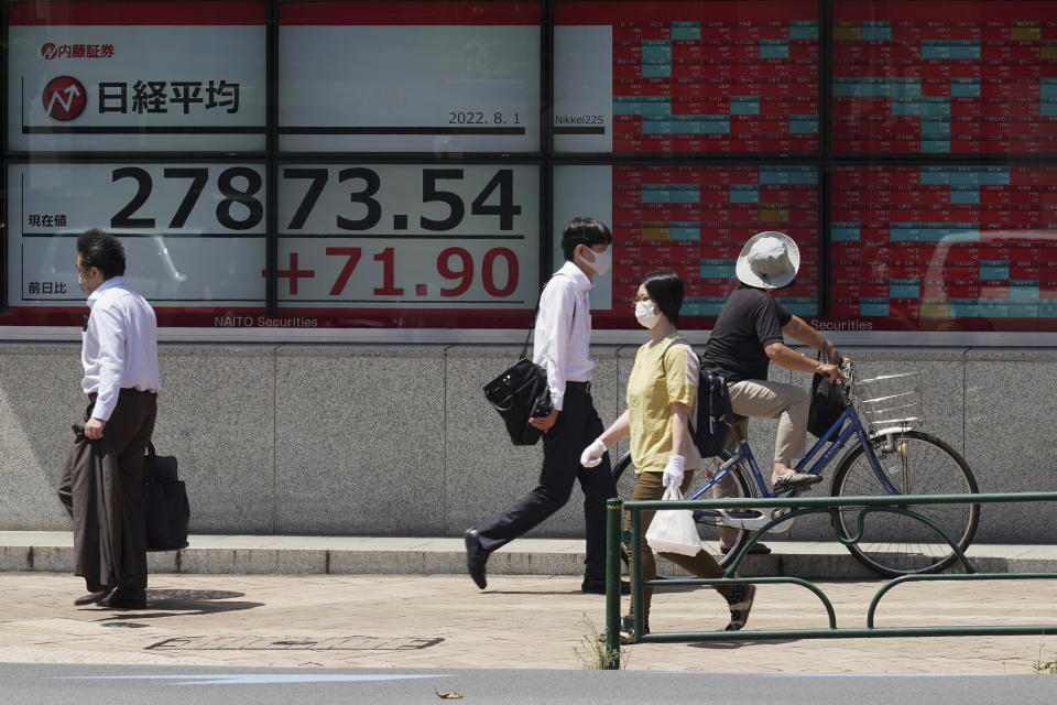 People wearing protective masks walk past an electronic stock board showing Japan's Nikkei 225 index at a securities firm Monday, Aug. 1, 2022, in Tokyo. Shares were mostly higher in Asia after a strong close on Wall Street last week, though the latest manufacturing surveys showed weakening factory activity in the region's biggest economies. (AP Photo/Eugene Hoshiko)