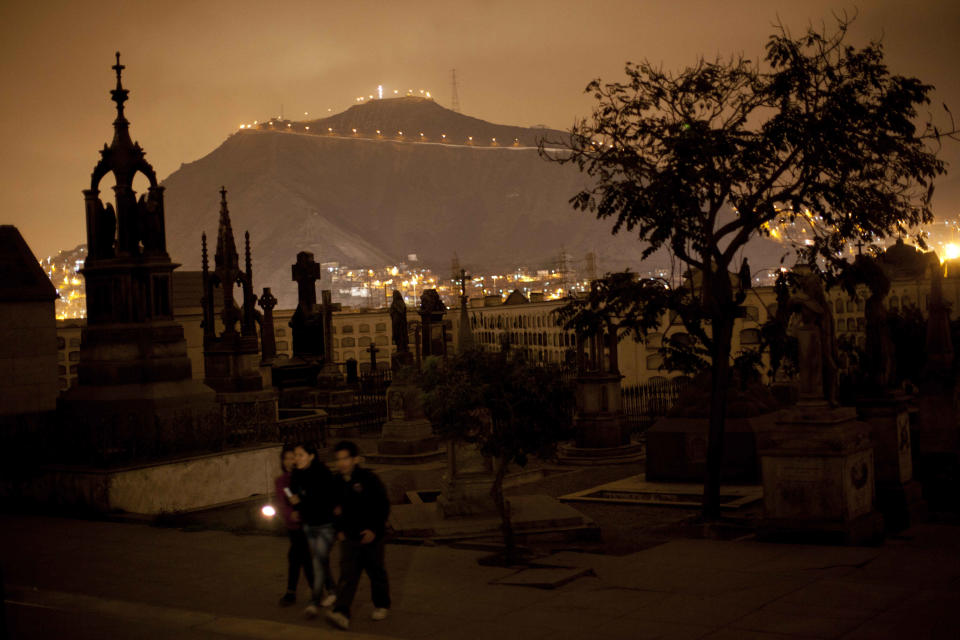 In this Dec. 6, 2012 photo, people use a flashlight as they take a nighttime guided tour through the Presbitero Matias Maestro cemetery in Lima, Peru. There are tombs of popular saints the Vatican doesn't recognize. The most popular is Ricardo Espiell, a child who died 119 years ago at age six after supposedly performing miracles. (AP Photo/Rodrigo Abd)