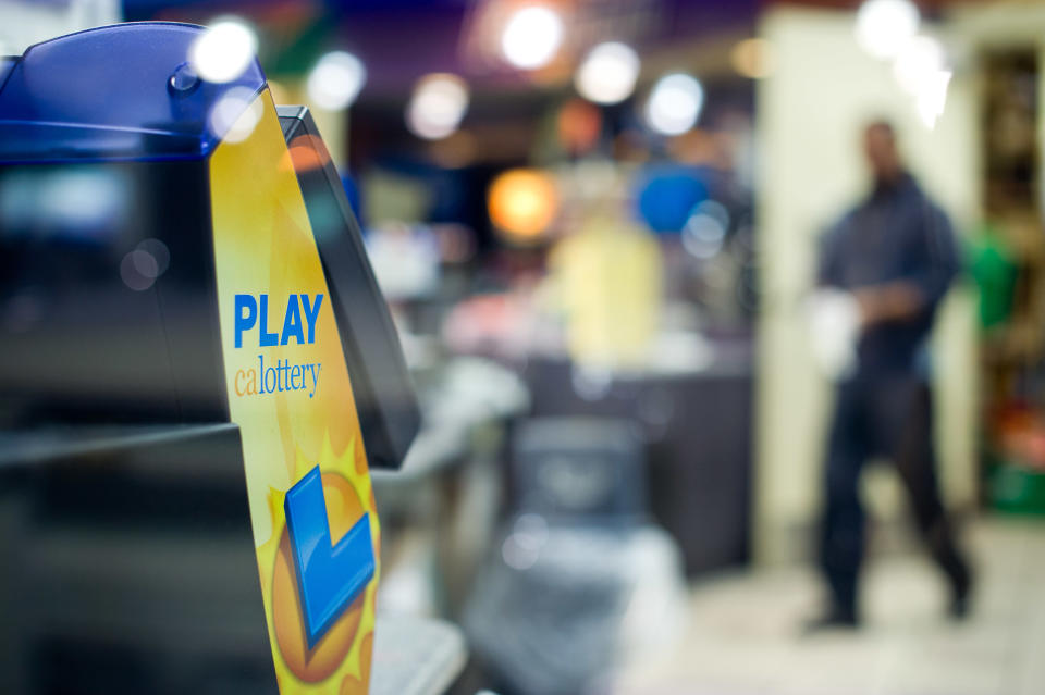 A worker passes a lottery ticket dispenser at Dixon Landing Chevron in Milpitas, Calif., on Thursday, Feb. 20, 2014. According to California lottery officials, the store sold the lone winning ticket for a $425 million Powerball jackpot but there was no immediate word on who may have won one of the largest lottery jackpots in U.S. history. (AP Photo/Noah Berger)