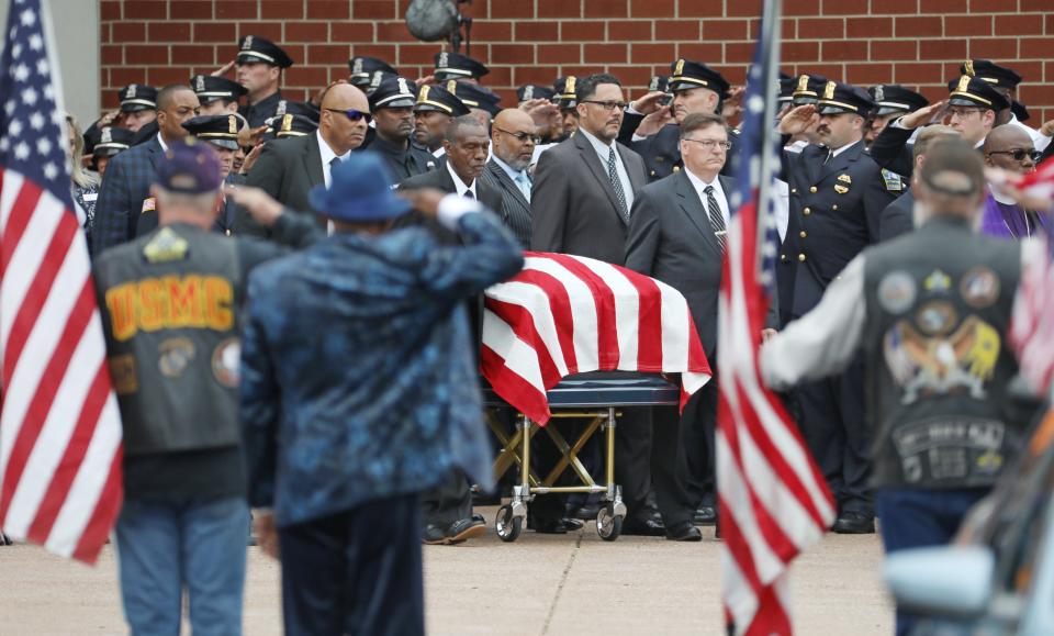 Law enforcement salute as the casket of Aaron W. Salter Jr. leaves the Chapel at Cross Point Wednesday, May 25, 2022 in Getzville following his funeral service.  Salter was killed during a mass shooting at a Buffalo area Tops grocery a week ago. 