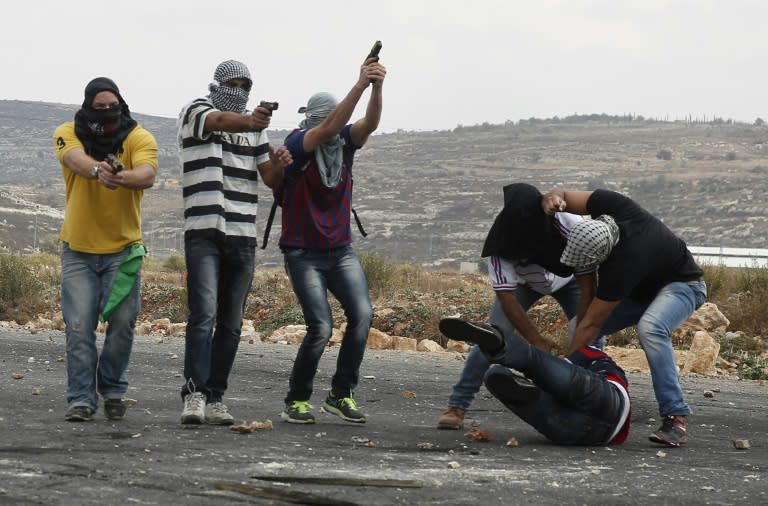 Members of the Israeli security forces detain a Palestinian stone thrower and aim their weapons at protesters during clashes in Beit El, on the outskirts of the West Bank city of Ramallah, on October 7, 2015