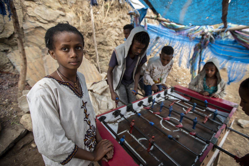 A girl watches while boys and young men play table football on the street, as Ethiopian Orthodox Christians celebrate Easter Sunday, in Gondar, in the Amhara region of Ethiopia Sunday, May 2, 2021. Ethiopia faces a growing crisis of ethnic nationalism that some fear could tear Africa's second most populous country apart, six months after the government launched a military operation in the Tigray region to capture its fugitive leaders. (AP Photo/Ben Curtis)