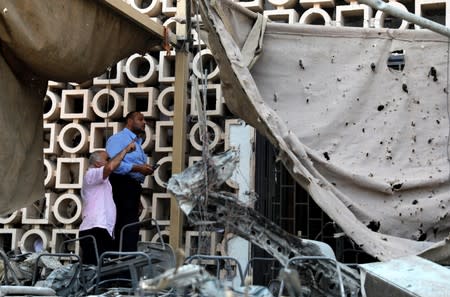 Egyptian investigators are seen in front of the damaged facade of the National Cancer Institute after an overnight fire from a blast, in Cairo