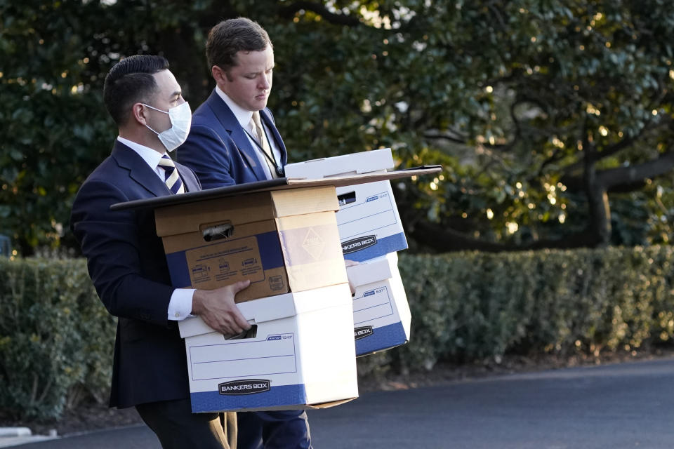 White House staff members, one wearing a mask, carry bankers boxes and a bulletin board to Marine One before President Donald Trump leaves the White House, Wednesday, Jan. 20, 2021, in Washington. Trump is en route to his Mar-a-Lago Florida Resort. (Alex Brandon/AP)         