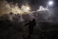 Migrants run as tear gas is thrown by U.S. Border Protection officers to the Mexican side of the border fence after they climbed the fence to get to San Diego, Calif., from Tijuana, Mexico, Tuesday, Jan. 1, 2019. Discouraged by the long wait to apply for asylum through official ports of entry, many migrants from recent caravans are choosing to cross the U.S. border wall and hand themselves in to border patrol agents. (AP Photo/Daniel Ochoa de Olza)