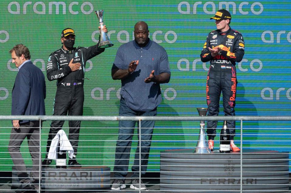 Second place Mercedes' British driver Lewis Hamilton (2nd L) celebrates alongside winner Red Bull's Dutch driver Max Verstappen (R) and former NBA star Shaquille O'Neal (C) after the Formula One United States Grand Prix at the Circuit of The Americas in Austin, Texas