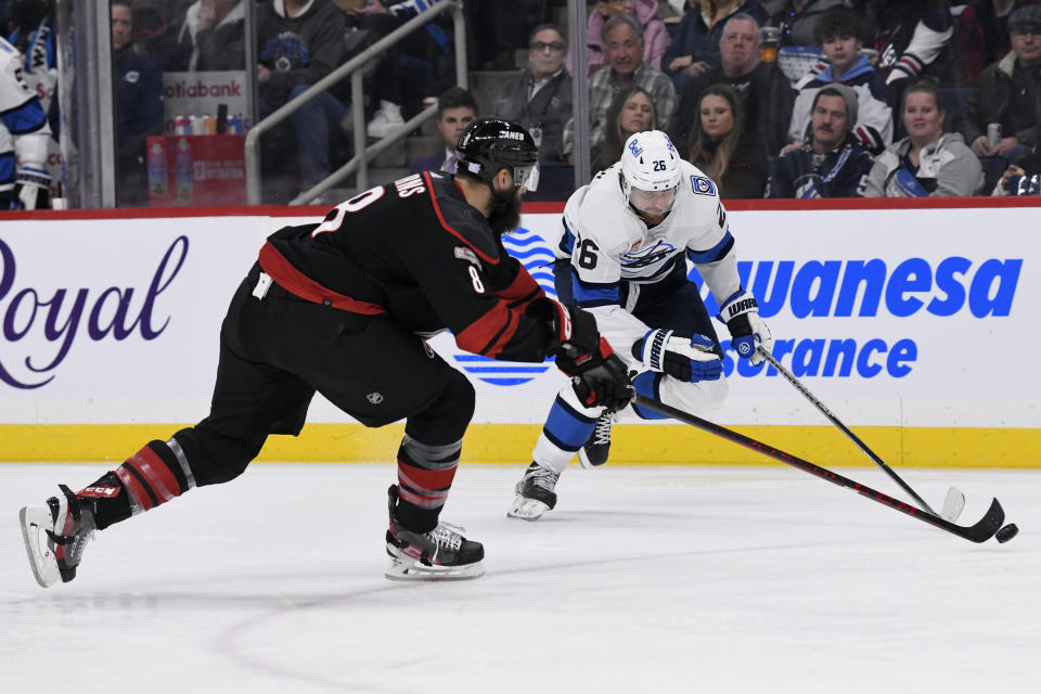 Winnipeg Jets' Blake Wheeler (26) skates past Carolina Hurricanes' Brent Burns (8) during the second period of an NHL hockey game in Winnipeg, Manitoba, Monday, Nov. 21, 2022. (Fred Greenslade/The Canadian Press via AP)