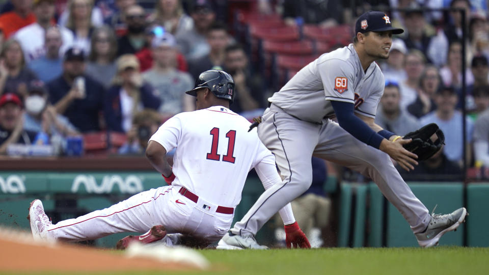 Boston Red Sox's Rafael Devers (11) slides past Houston Astros third baseman Aledmys Diaz on a triple during the first inning of a baseball game at Fenway Park, Wednesday, May 18, 2022, in Boston. (AP Photo/Charles Krupa)