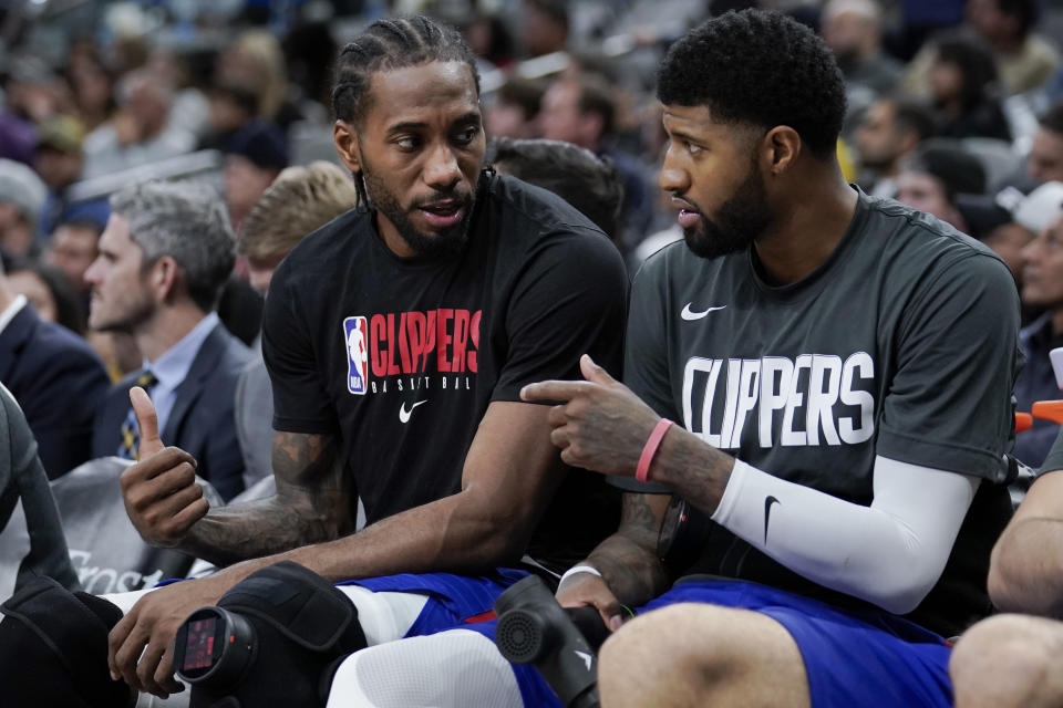 Los Angeles Clippers' Kawhi Leonard, left, and Paul George talk on the bench during the second half of an NBA basketball game against the San Antonio Spurs, Saturday, Dec. 21, 2019, in San Antonio. Los Angeles won 134-109. (AP Photo/Darren Abate)