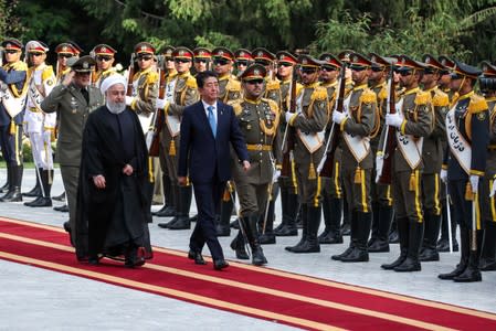 Iranian President Hassan Rouhani walks with Japan's Prime Minister Shinzo Abe, during a welcome ceremony in Tehran