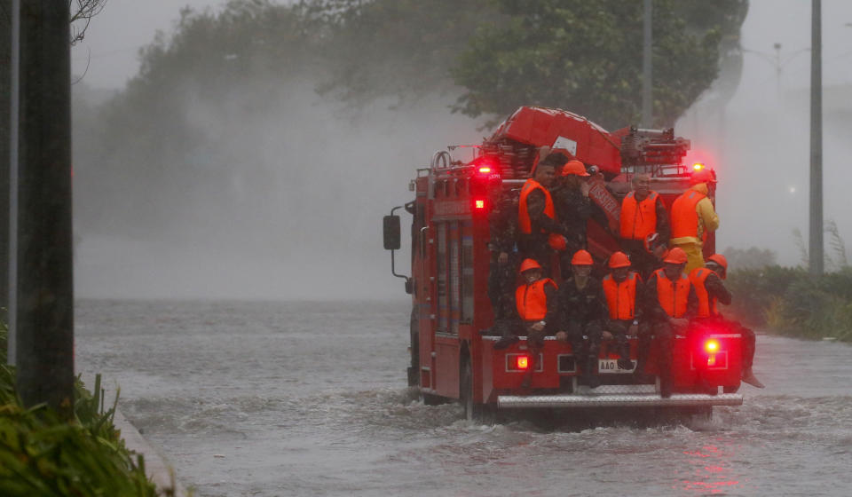 Fire rescuers head to low-lying areas in Manila under heavy rains and strong winds brought about by Typhoon Mangkhut which also barreled into northeastern Philippines before dawn Saturday, Sept. 15, 2018 in Manila, Philippines. The typhoon slammed into the Philippines' northeastern coast early Saturday, its ferocious winds and blinding rain ripping off tin roof sheets and knocking out power, and plowed through the agricultural region at the start of the onslaught.(AP Photo/Bullit Marquez)