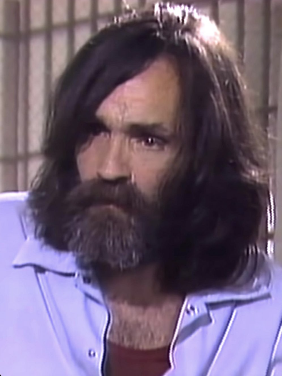 close up of Charles Manson with shoulder-length hair and beard