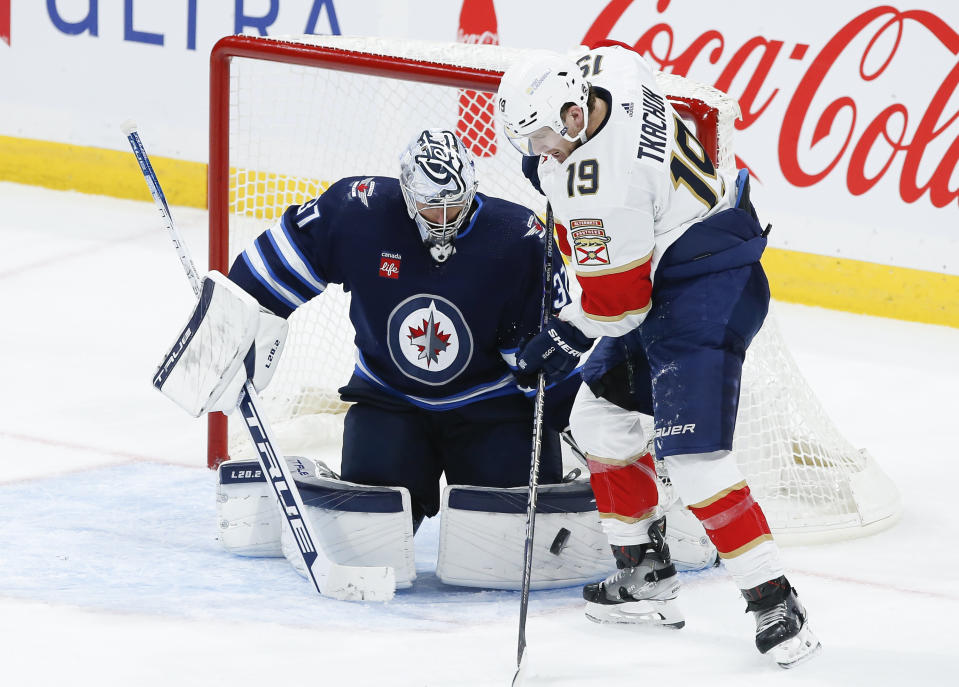 Winnipeg Jets goaltender Connor Hellebuyck (37) saves a deflection by Florida Panthers' Matthew Tkachuk (19) during third-period NHL hockey game action in Winnipeg, Manitoba, Saturday, Oct. 14, 2023. (John Woods/The Canadian Press via AP)