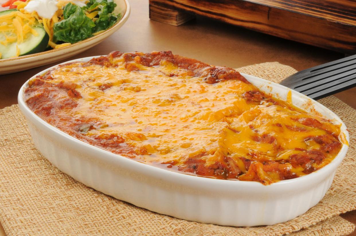 A chicken enchillada casserole topped with cheddar cheese