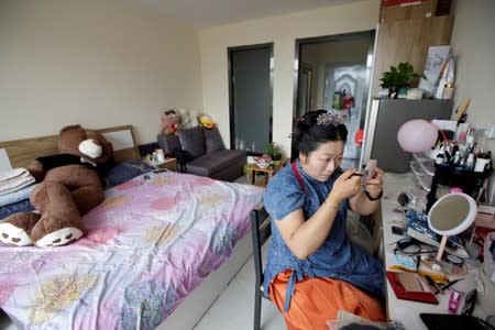 Li Doudou applies makeup before attending a performance of the "guqin" traditional musical instrument, at her rental home in Hebei province, China