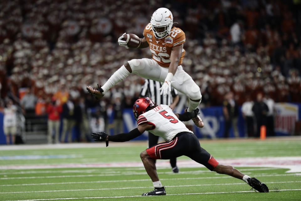 Texas running back Keaontay Ingram (26) leaps over Utah defensive back Tareke Lewis (5) during the second half of the Alamo Bowl NCAA college football game in San Antonio, Tuesday, Dec. 31, 2019. (AP Photo/Eric Gay)