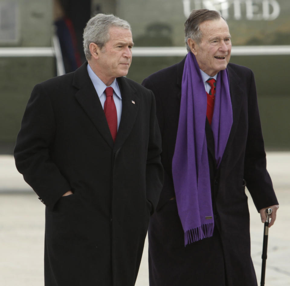 FILE - In this Dec. 26, 2008 file photo, President George W. Bush walks with his father, former President George H.W. Bush, at Andrews Air Force Base, Md. Presidents George H.W. Bush and George W. Bush were both conservatives, but during very different times. The elder Bush was a Republican who could carve an occasional moderate path without a crushing response from the right. His was an era of stepping back from the prospect of doomsday, with the collapse of the Soviet Union, and a far more limited threat emerging with Iraq’s invasion of Kuwait. But that was not at all like the Sept. 11 terrorist attacks that came early to his son. (AP Photo/Evan Vucci, File)