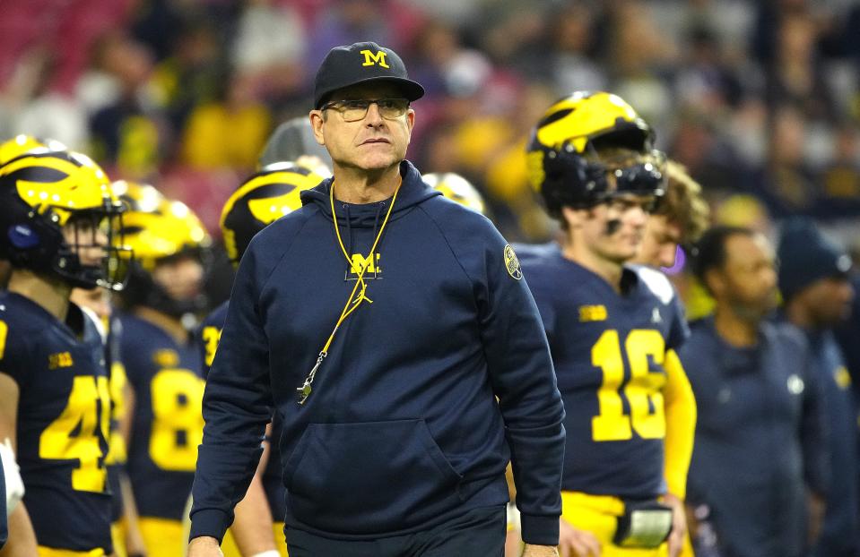 Michigan coach Jim Harbaugh walks the sideline during the warmups prior to his team's game against TCU in the 2022 Fiesta Bowl at State Farm Stadium.