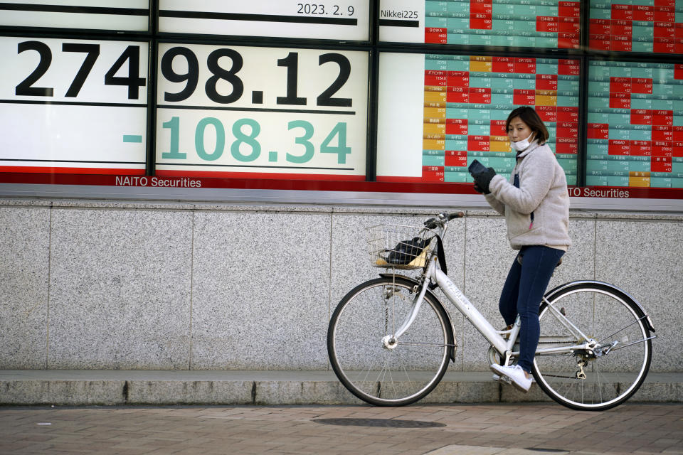 A person on a bicycle stops in front of an electronic stock board showing Japan's Nikkei 225 index at a securities firm Thursday, Feb. 9, 2023, in Tokyo. Shares fell Thursday in Asia after Wall Street gave back some of its recent gains on persisting uncertainty over interest rates and inflation. (AP Photo/Eugene Hoshiko)