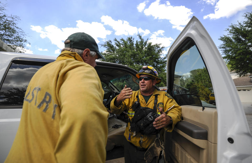 John DeWolfe, with Florida Forest Service, right, speaks with coworker Mike Penn along a street in the Suncoast Lakes subdivision Tuesday, April 11, 2017 in Land O' Lakes, Fla. The Silver Palms Fire burned close to homes in the Suncoast Lakes subdivision Tuesday forcing residents to use garden hoses on vegetation and roofs around their property. (Chris Urso/The Tampa Bay Times via AP)