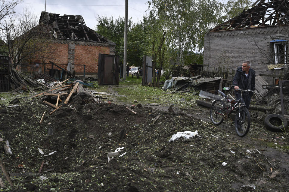 A man walks next to a crater created by an explosion after an overnight Russian attack in Kramatorsk, Ukraine, Tuesday, Oct. 4, 2022. (AP Photo/Andriy Andriyenko)