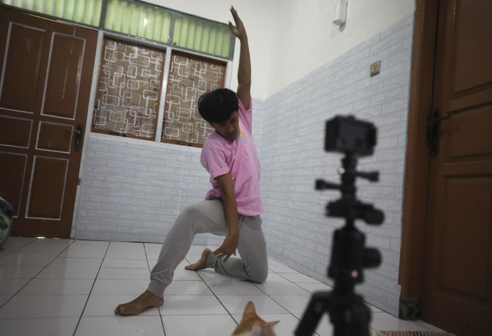 Dancer Siko Setyanto performs a dance while recording it using an action camera mounted on a tripod at his one-bedroom rented house in Jakarta, Indonesia Thursday, May 14, 2020. Two Indonesian choreographers are helping fellow dancers who lost their jobs due to the new coronavirus outbreak in the country by setting up a YouTube channel as a platform where dancers, choreographers and dance teachers can perform, then receive donation from viewers. (AP Photo/Dita Alangkara)