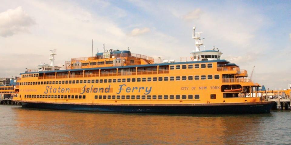 An orange Staten Island ferry docked in a harbour.