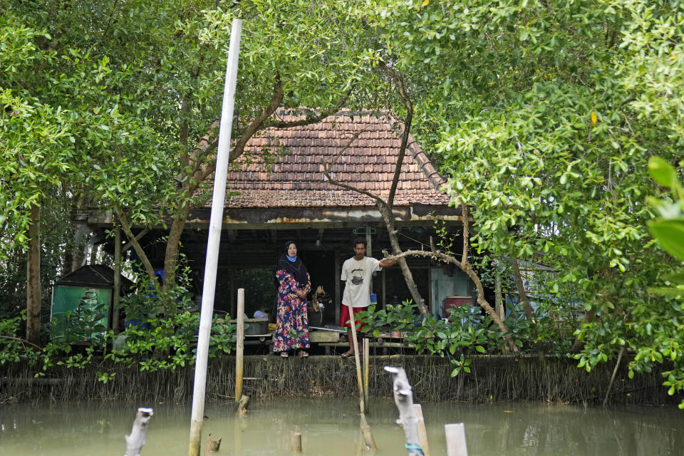 Asiyah (izq) y su esposo Aslori posan para una foto en la casa que abandonaron en Mondoliko (Java, Indonesia) tras quedar inhabitable por la crecida del mar. Foto del 5 de septiembre del 2022. (AP Photo/Dita Alangkara)