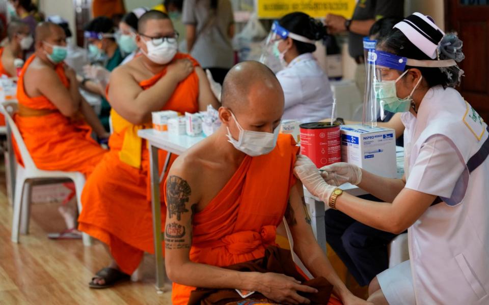 Health workers administer doses of the AstraZeneca vaccine to Buddhist monks at the Wat Srisudaram in Bangkok - AP