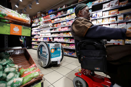 A man does his shopping at a store using an autonomous robot, shaped and inspired by Star Wars R2D2, in a test for the delivery of groceries by Franprix supermarket chain in the 13th district of Paris, France, April 17, 2019. REUTERS/Charles Platiau