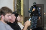 A Russian Federal Bailiffs Service employee guards a corridor leading to a courtroom as journalists sit inside the court in Yekaterinburg, Russia, Thursday, July 18, 2024, during a hearing of Wall Street Journal reporter Evan Gershkovich's suspected spying activities. (AP Photo/Dmitri Lovetsky)