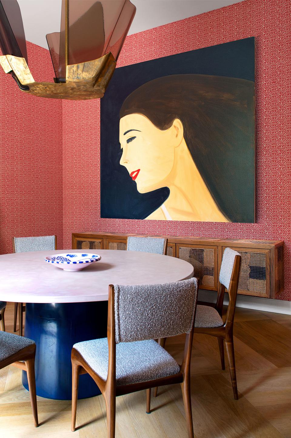 An Alex Katz portrait is displayed in the dining room. Vincenzo de Cotiis pendant; Lola Lely table; Carlo de Carli chairs; on walls, woven silk by Fortuny.