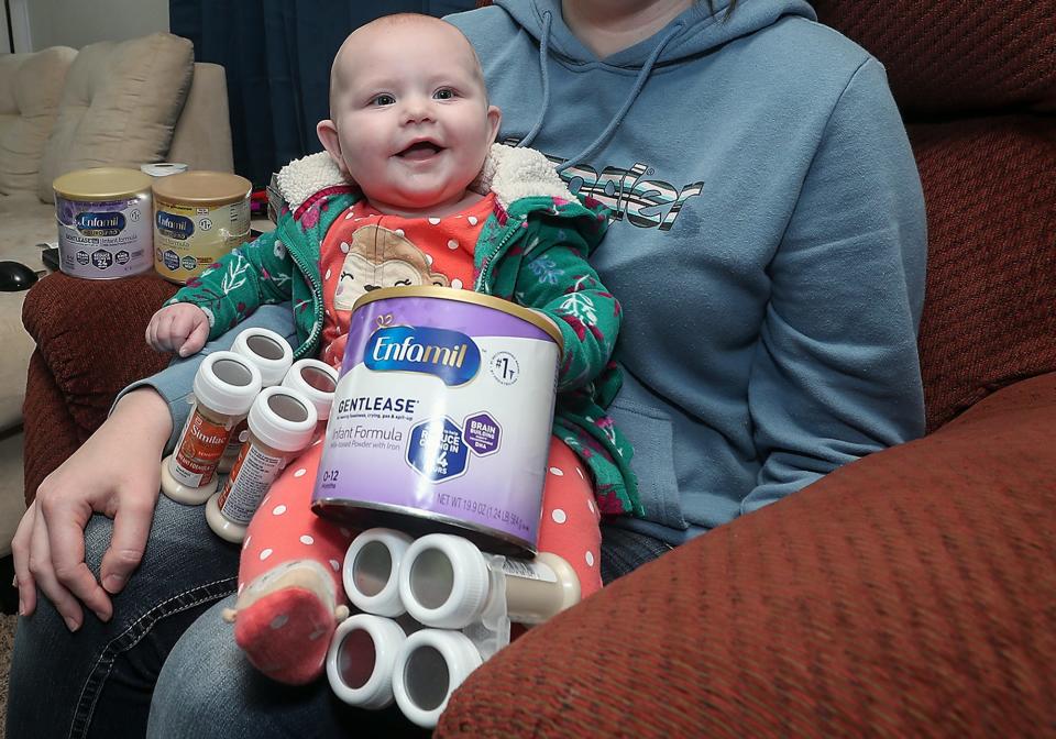 Sarah van Uitert's daughter Eliza sits in her moms lap next to containers of formula at their home in South Kitsap on Thursday.