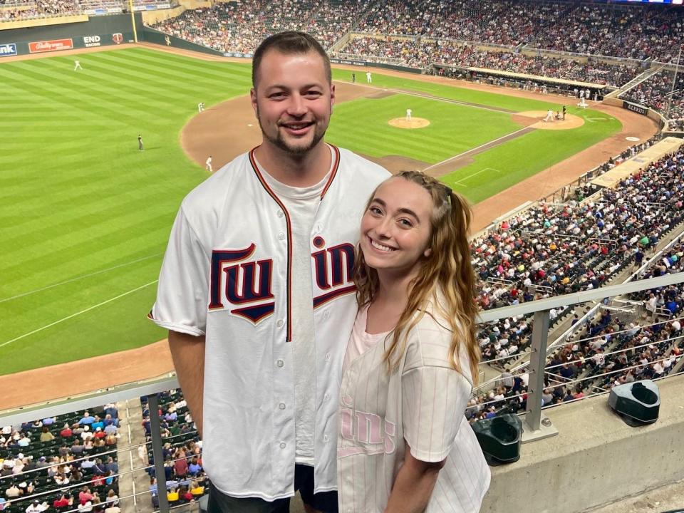 A man and woman standing together in a baseball stadium.