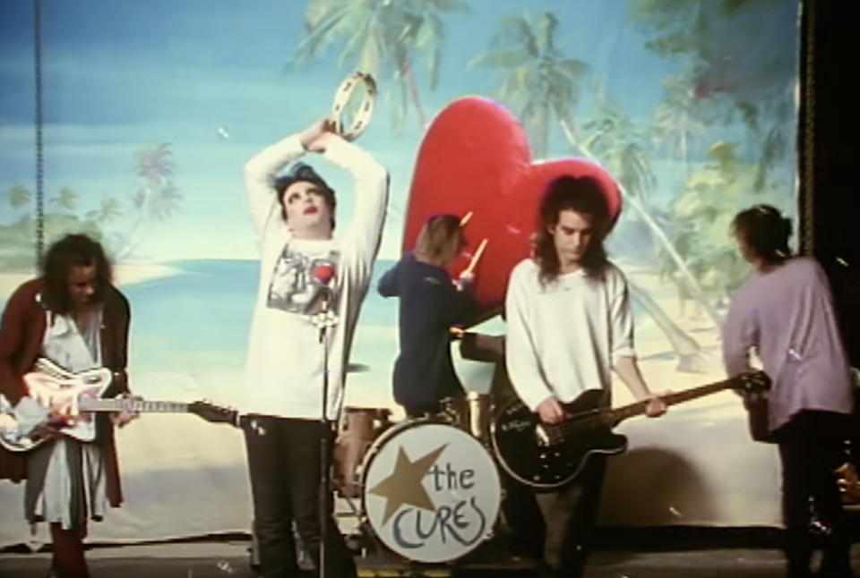 The Cure plays in front of a heart and palm trees