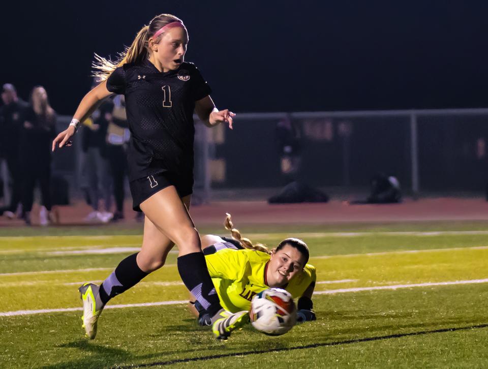 Johnson Jaguars forward Drew Taylor (1) kicks the ball for the goal as Lake Travis Cavaliers goalkeeper Colette Whitsitt tries to make a play during the second half at the District 26-6A girls soccer game on Friday, Feb 9, 2024 at Johnson High School in Buda, TX.