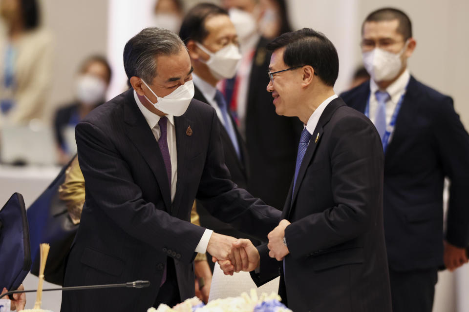 China's Foreign Minister Wang Yi, left, and Hong Kong Chief Executive John Lee shake hands during the APEC Leaders' Informal Dialogue with Guests during the Asia-Pacific Economic Cooperation (APEC) Summit in Bangkok, Thailand on Nov. 18, 2022. The Hong Kong government said Monday, Nov. 21, 2022 that leader John Lee tested positive for COVID-19 after returning from the Asia-Pacific Economic Cooperation meetings in Thailand. (Athit Perawongmetha/Pool Photo via AP)