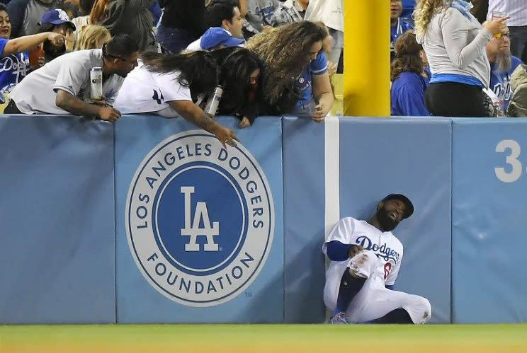 Dodgers left fielder Andrew Toles writhes after running into the left field wall while trying to catch a ball hit during Tuesday's game at Dodger Stadium. (AP)