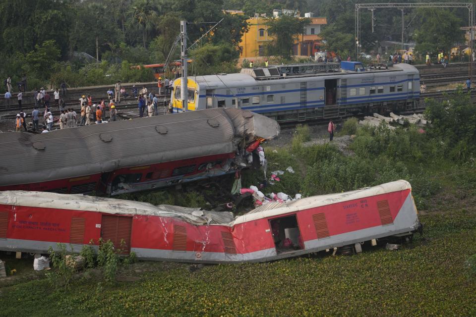 People watch at the site where trains that derailed, in Balasore district, in the eastern Indian state of Orissa, Sunday, June 4, 2023. Indian authorities end rescue work and begin clearing mangled wreckage of two passenger trains that derailed in eastern India, killing over 300 people and injuring hundreds in one of the country’s deadliest rail crashes in decades. (AP Photo/Rafiq Maqbool)