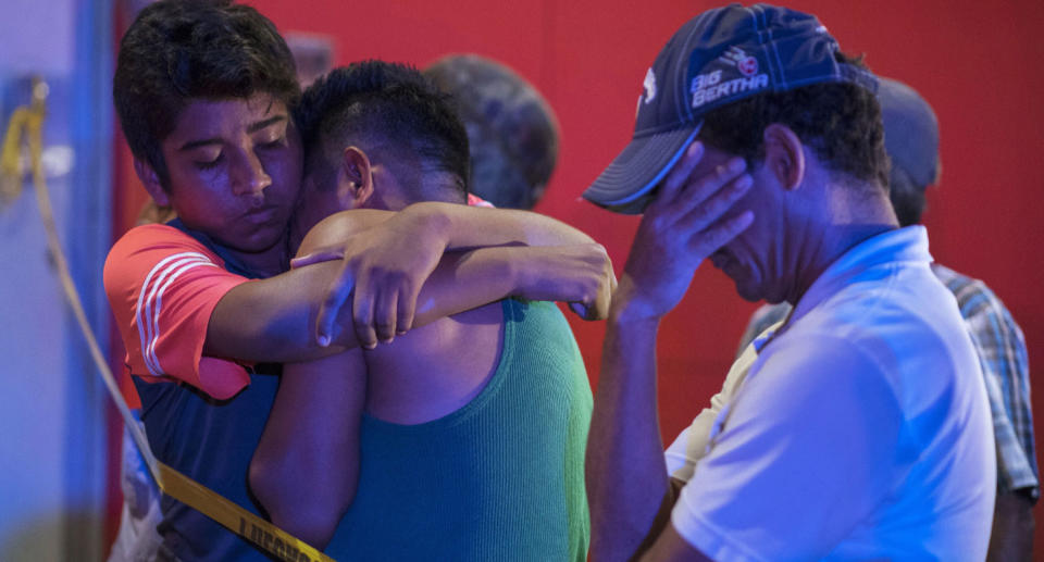 People crying outside Bar Caballo Blanco where 26 people died after a gang lit a fire inside.